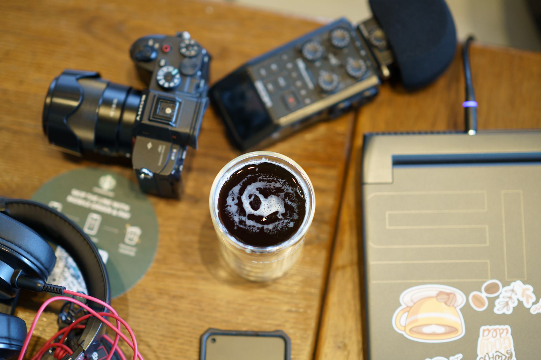 Vue aérienne d'un espace de travail avec une caméra, des écouteurs, du matériel audio et une tasse de café.