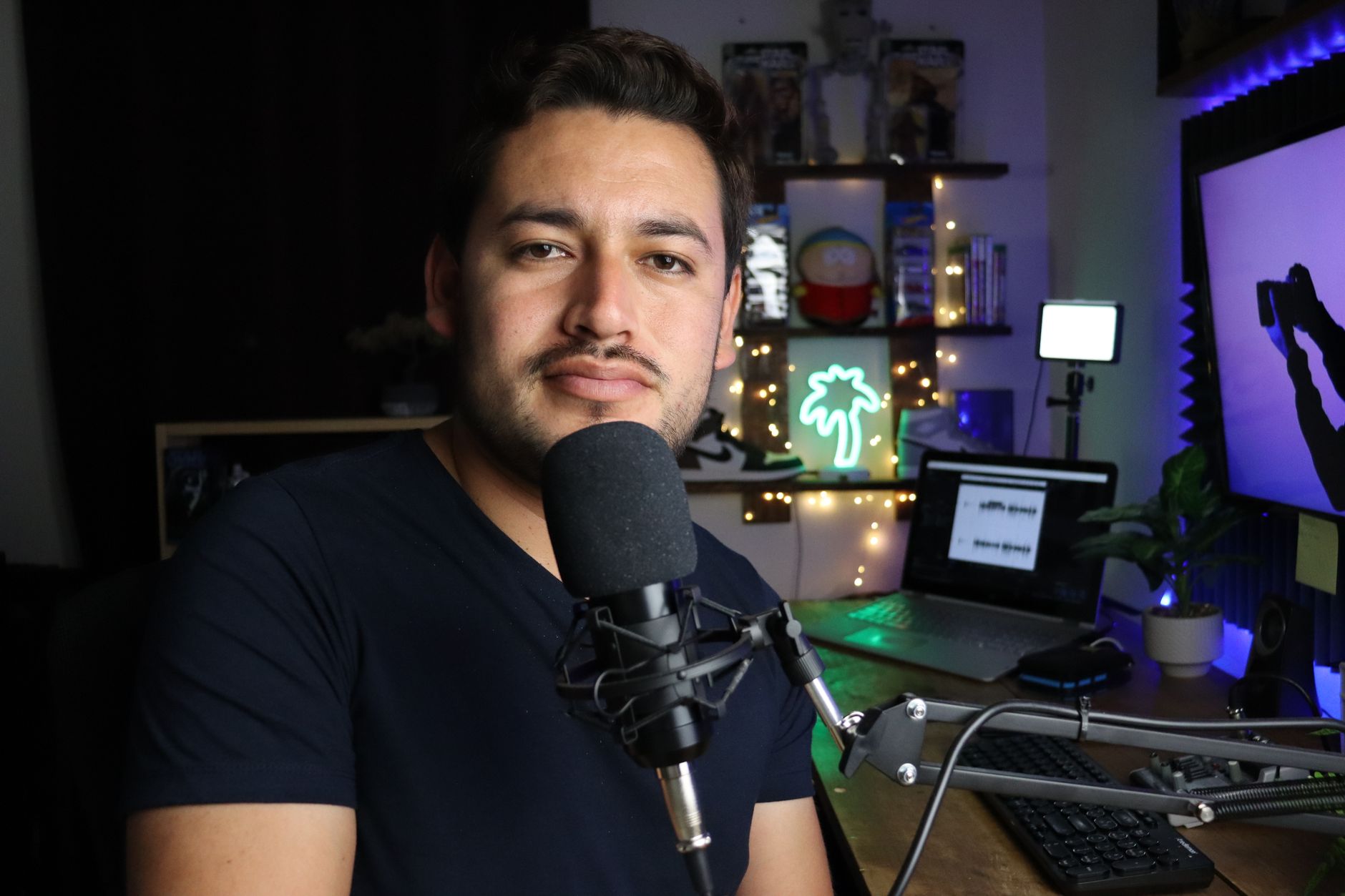 Un podcasteur dans un studio à domicile avec éclairage néon et équipement technique.