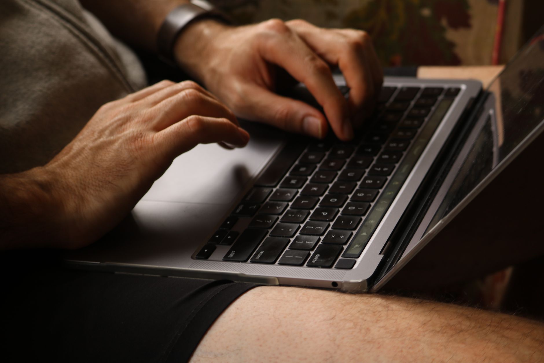 Frappe sur un clavier d'ordinateur portable, gros plan des mains dans un cadre intérieur décontracté.
