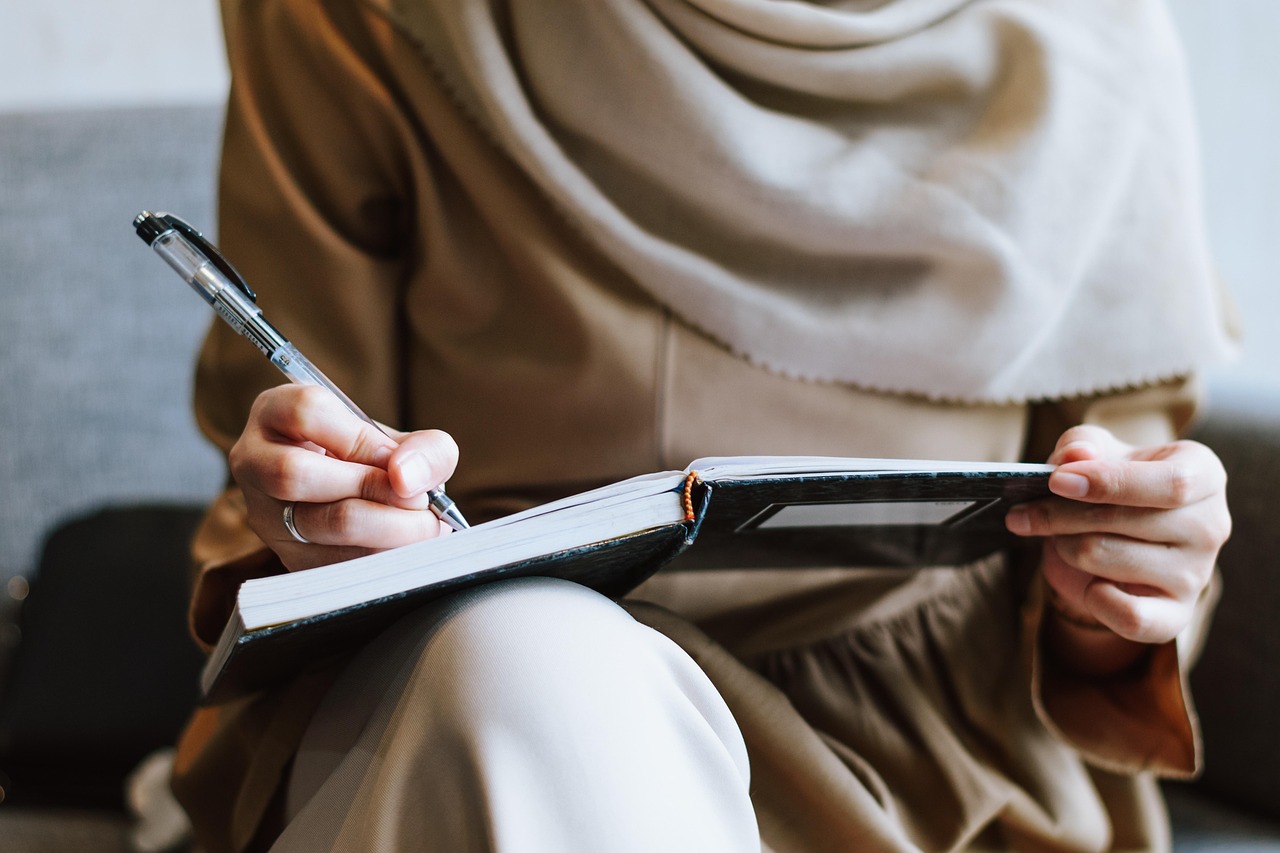 Femme musulmane écrivant dans un cahier en réunion d'affaires dans un café.